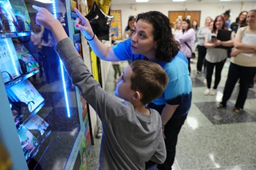 Teacher helps a student make a selection from Inchy's Bookworm Vending Machine